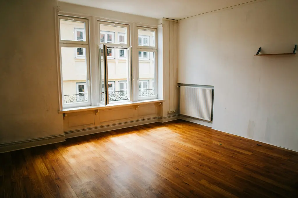 Empty new flat with a large window and wooden flooring, ready for a pre-possession inspection
