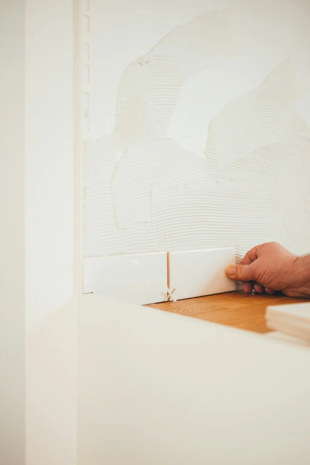Tiler fixing a white wall tile